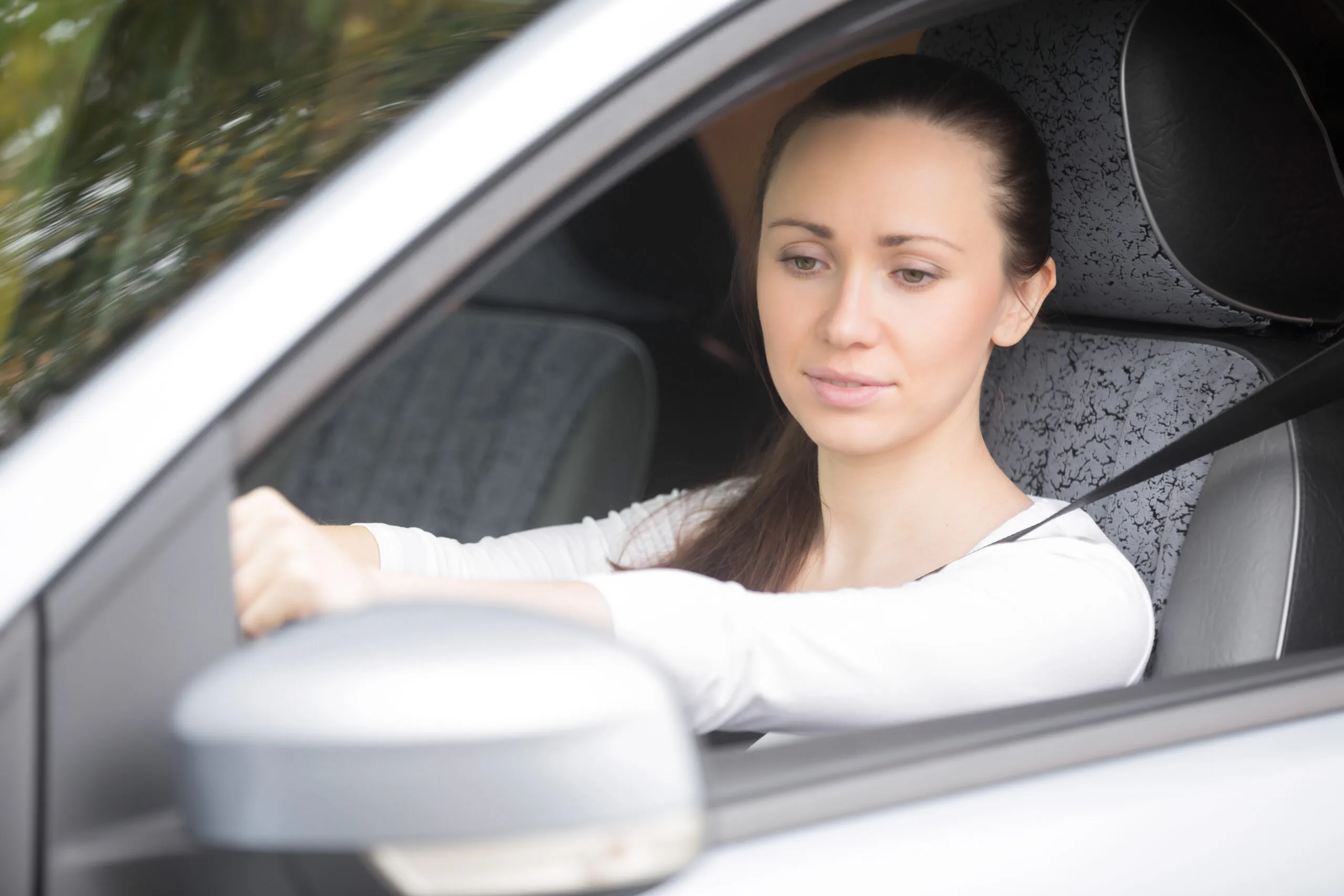 Woman buckling a seat belt in the drivers seat, safety belt, to secure against harmful movement during a collision or a sudden stop